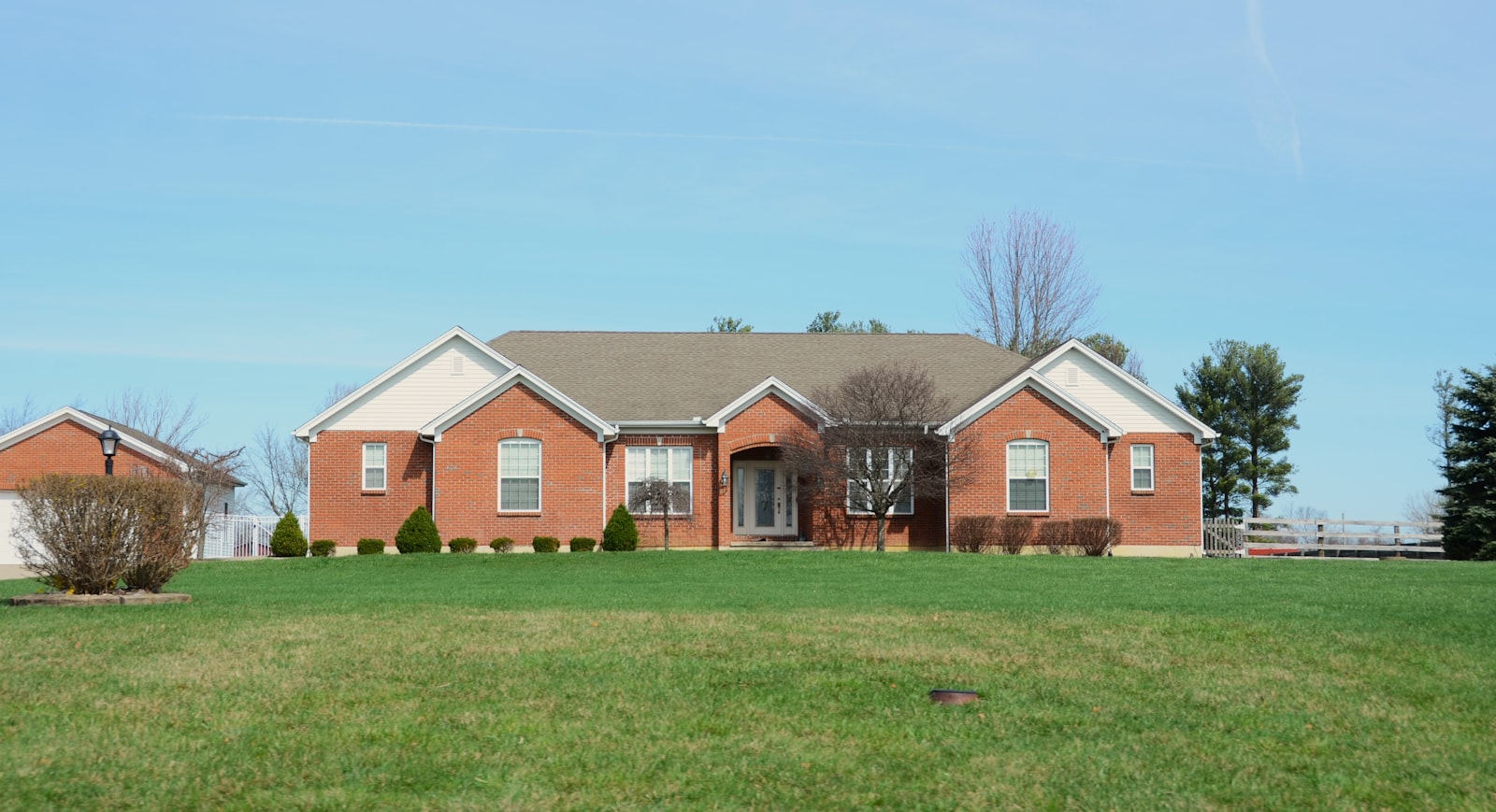 Brick Buda home with a freshly mowed lawn, edged drive, and trimmed hedges.